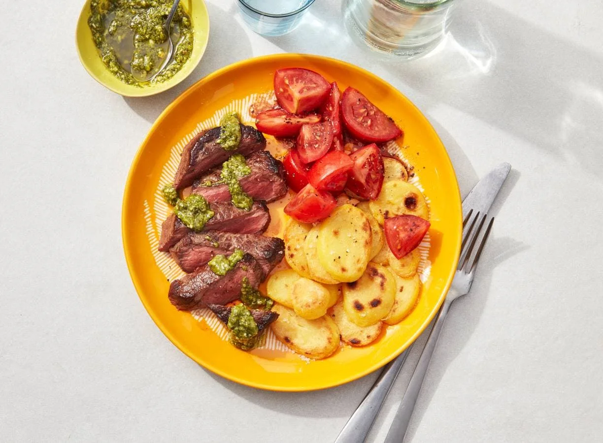 Biefstuk met pesto, aardappelschijfjes en tomatensalade