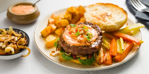 Beyond Meat burger met gebakken uitjes op vegan brioche met Nicola aardappels, bleekselderij, roodlof en peen uit de oven